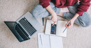 A young person with notebooks, calculator and laptop thinking about things to consider when creating a solid financial plan