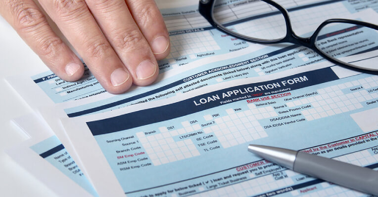 Close-up view of a man's hand on a loan application form