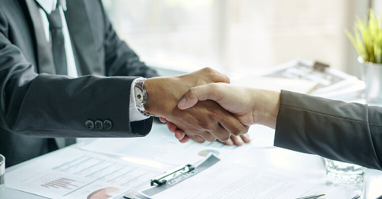 Close-up of two people in business suit shaking hands over contract on table, illustrating right way of borrowing money smartly the legal way