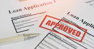 Close-up of loan application form stamped with 'Approved' in red ink