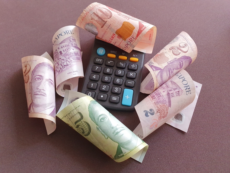 Different denominations of Singapore money and a calculator representing ways to pay off fast cash loans in Singapore
